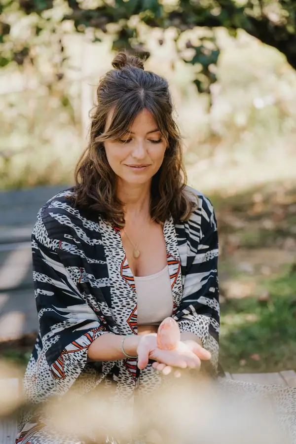 Luisa sitzt im Garten und hält einen Kristall in den Händen